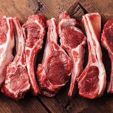Meat delivery Dubai: Fresh, tender raw meat cuts on a wooden board, ready for cooking, with herbs and spices on the side.