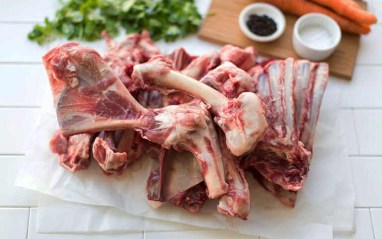 Meat delivery Dubai: Fresh, tender raw meat cuts on a wooden board, ready for cooking, with herbs and spices on the side.
