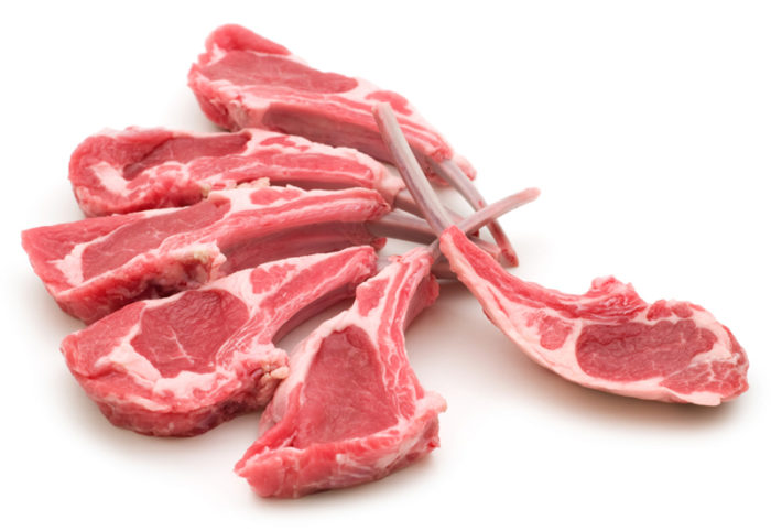 Meat delivery Dubai: Fresh, tender raw meat cuts on a wooden board, ready for cooking, with herbs and spices on the side.