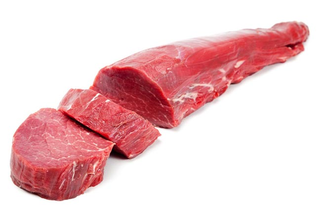 Meat delivery Dubai: Fresh, tender raw meat cuts on a wooden board, ready for cooking, with herbs and spices on the side.