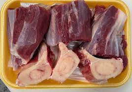 Meat delivery Dubai: Fresh, tender raw meat cuts on a wooden board, ready for cooking, with herbs and spices on the side.